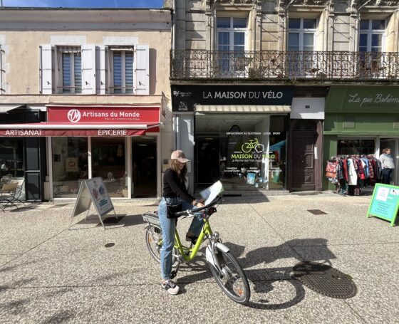 Jeune cycliste devant la Maison du Vélo à La Roche-sur-Yon qui tient dans ses mains la carte des aménagements cyclables